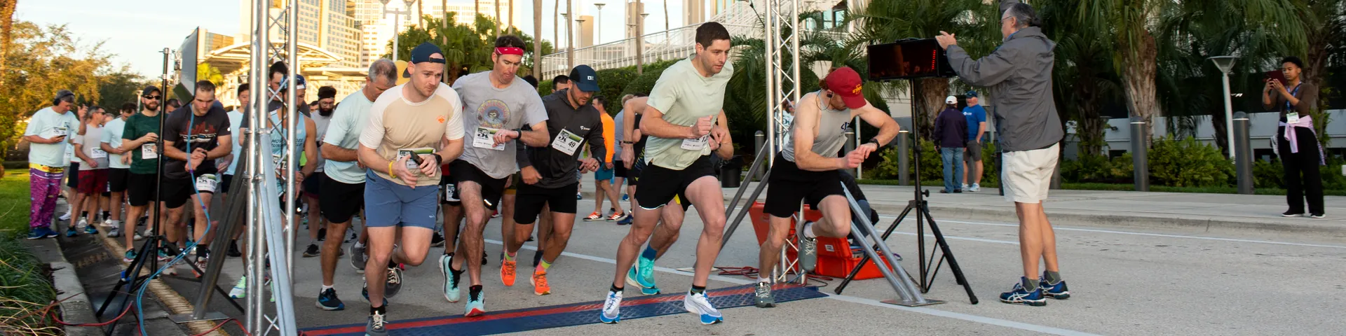 Runners crossing the start line under a Health in Action 5K banner outside the convention center.
