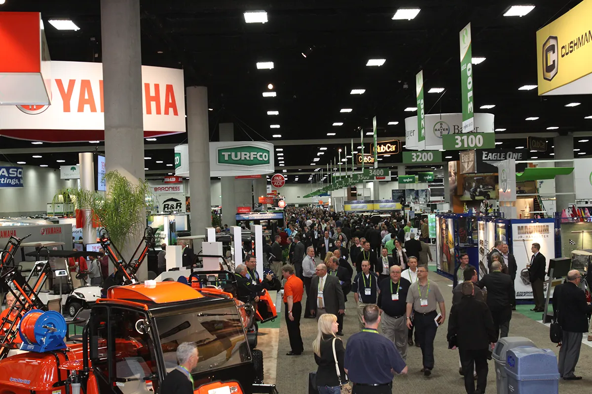 Trade show floor aisle with exhibitor booths and attendees browsing